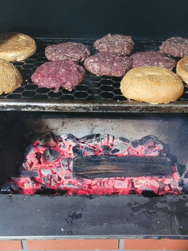 Burgers and buns on the grate over a bed of red embers