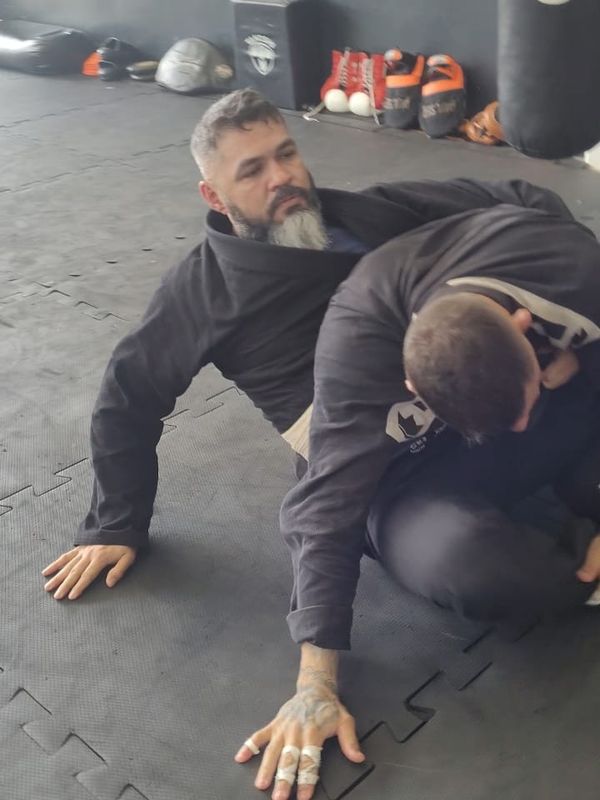 Ed in a black gi on the mat, attentive, during training