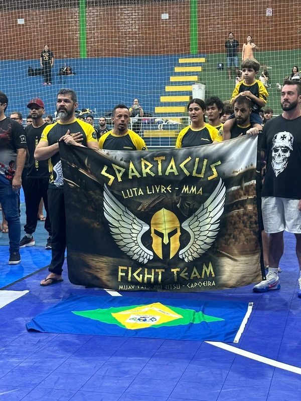 The team lined up behind the Spartacus Fight Team banner, hands on chests, before a competition