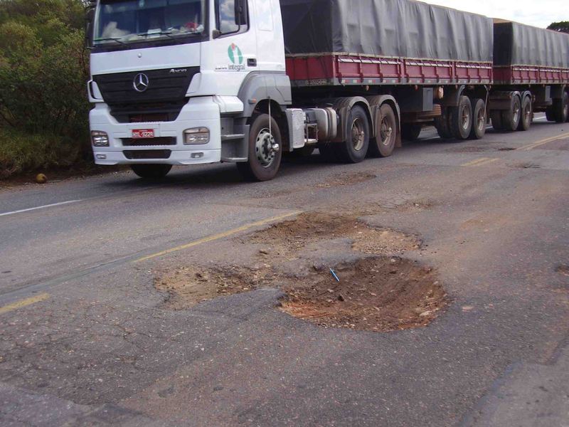 A truck steering around a crater in the asphalt of the BR-116 highway