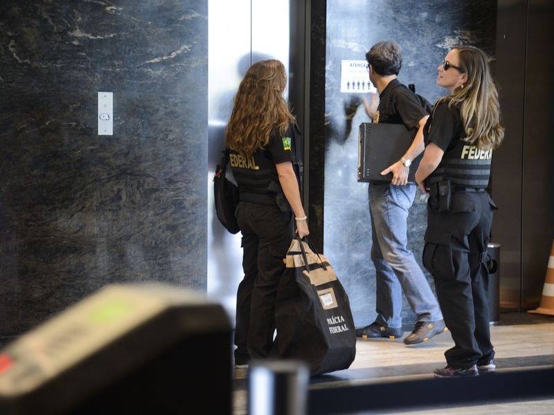 Federal Police agents leaving a building with seized computers and documents